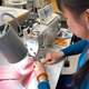An employee of Kaas Tailored sews a mask